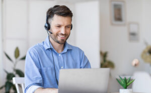 Call center operator at work. Male manager wearing headset and using laptop
